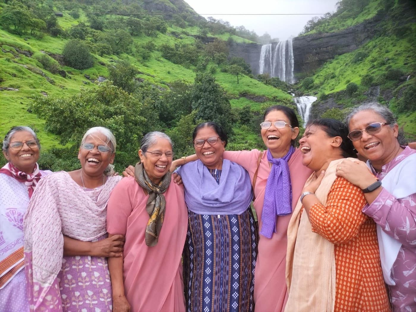 A group of senior women laughing together in front of a waterfall